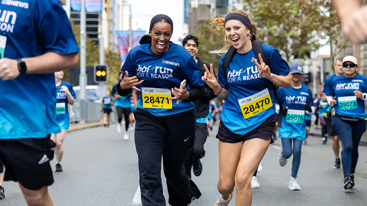 Two young female participants smiling as they run past