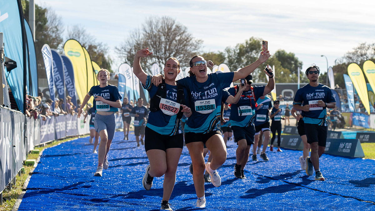 Two HBF Run for a Reason participants taking selfies as they cross the finish line