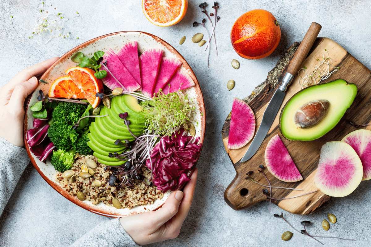 A plate of colourful, healthy food including fruit, avocado and green vegetables.