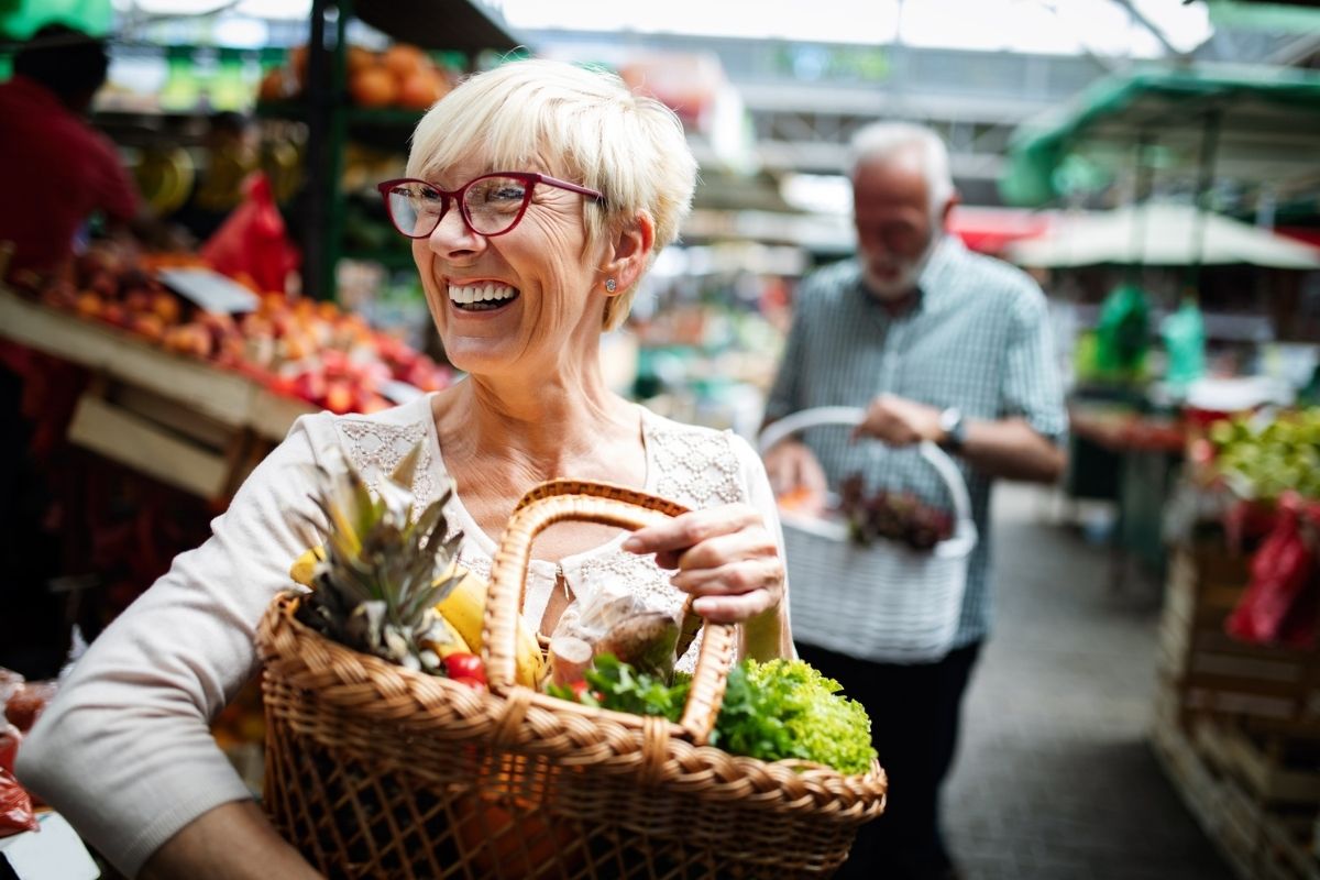 A mature woman laughing as she shops for healthy fruit and vegetables