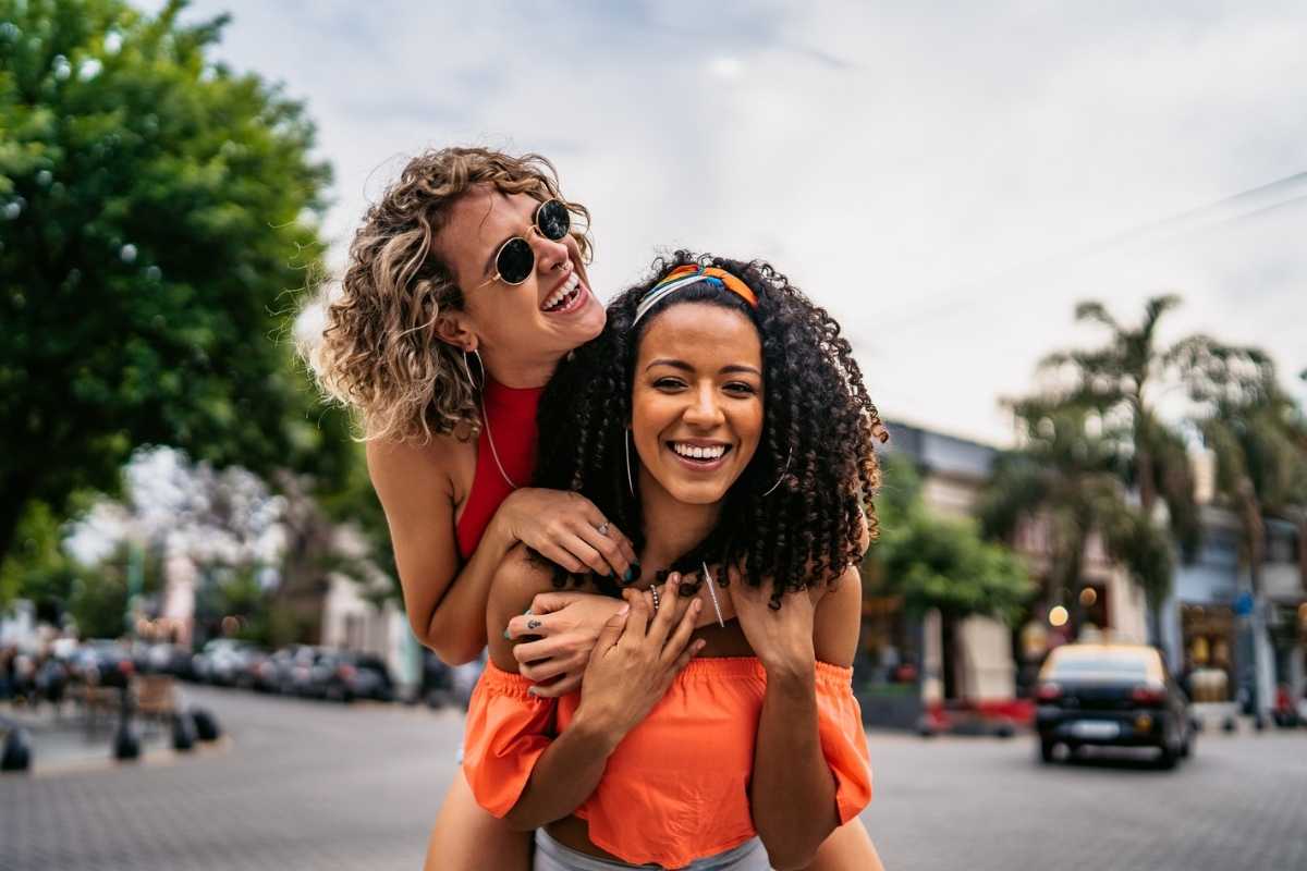 Two young woman hugging and having fun on a colourful street