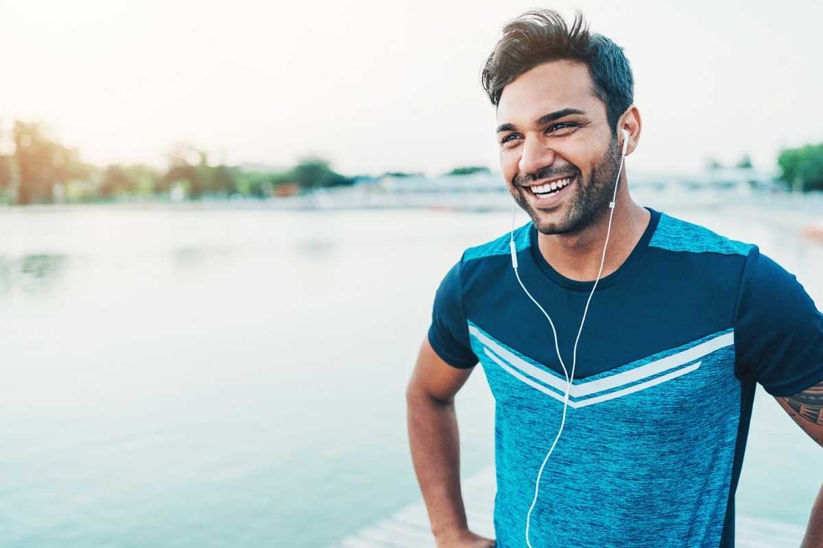 A young man smiling after exercise by the water