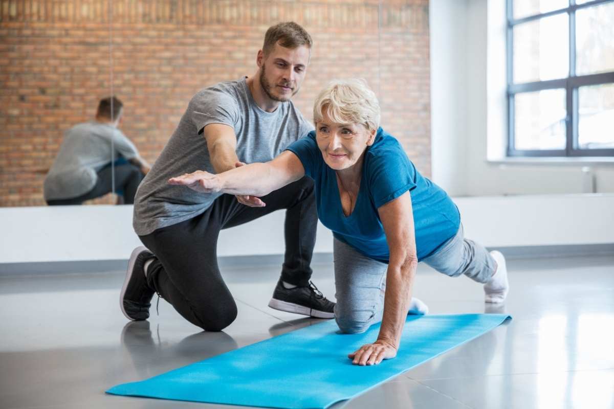 A physiotherapist helping a mature woman with strength and mobility exercises
