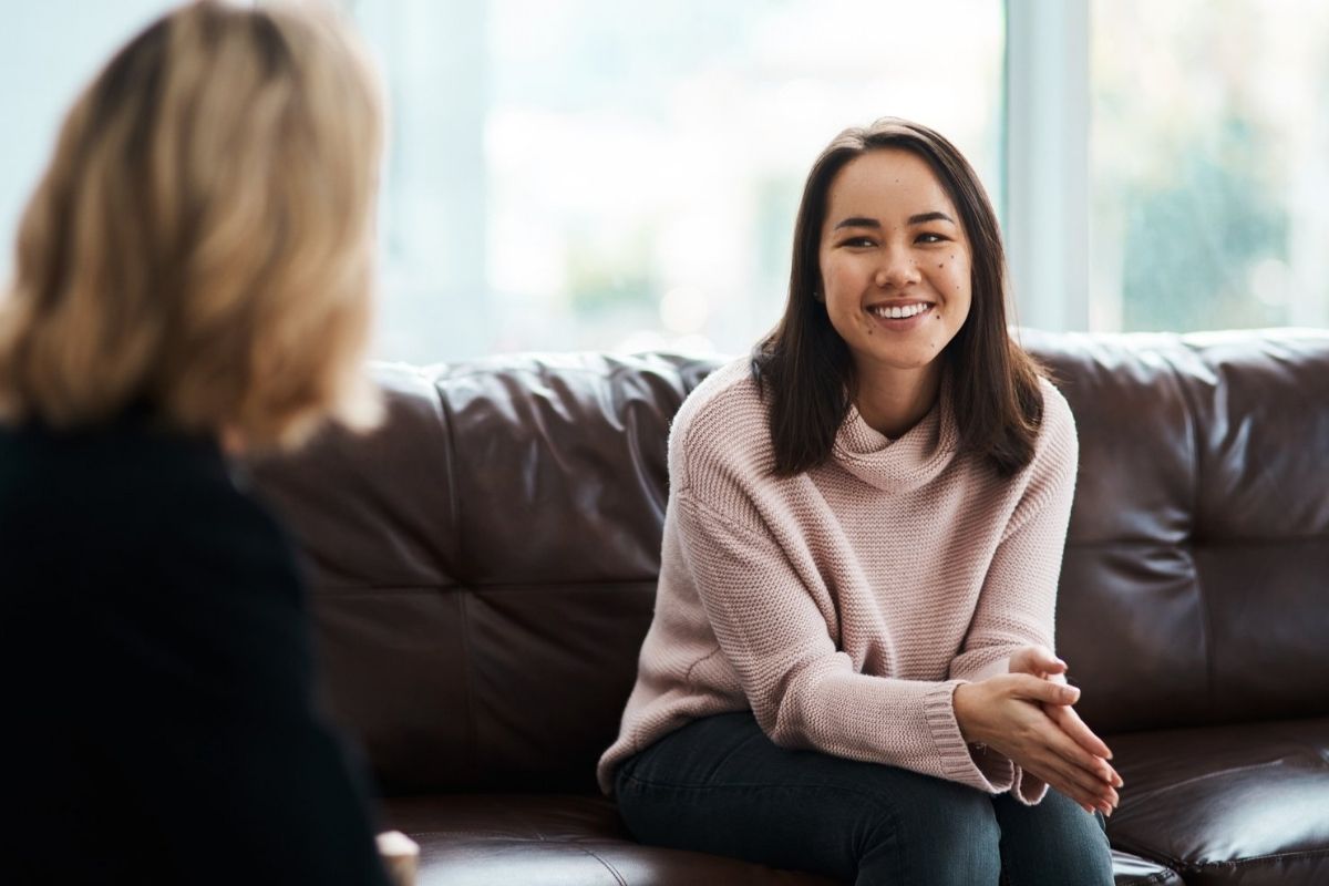 A young woman sitting on a couch and talking to a psychologist