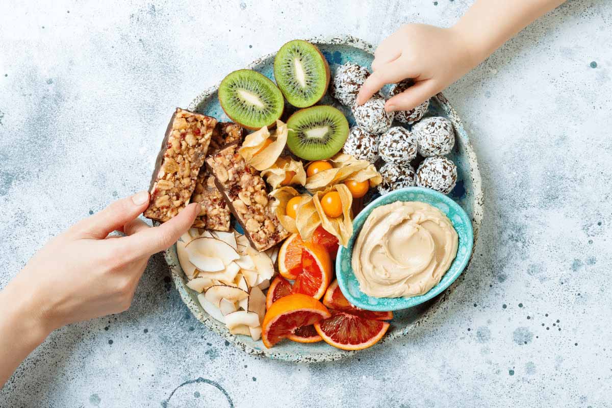 A plate of healthy snacks with hands reaching for them