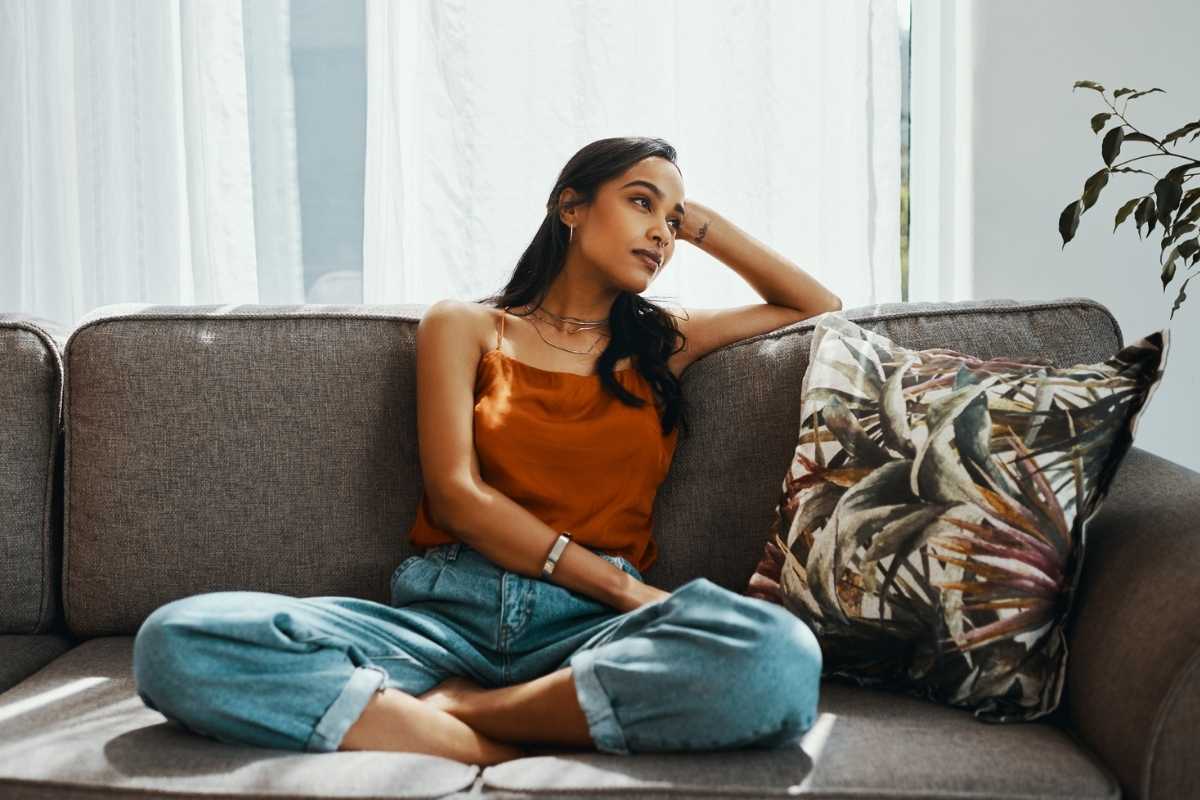A young woman on the couch looking lost in thought