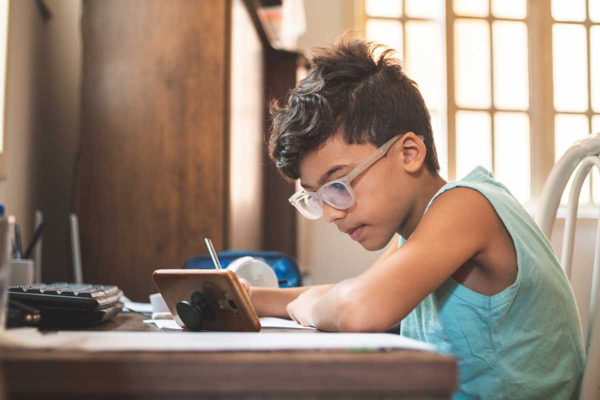 A cute little boy wearing glasses, doing his homework