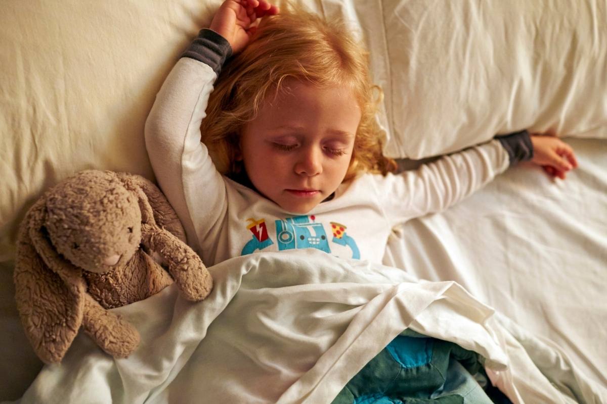 Three year old little girl sleeping with teddy in bed