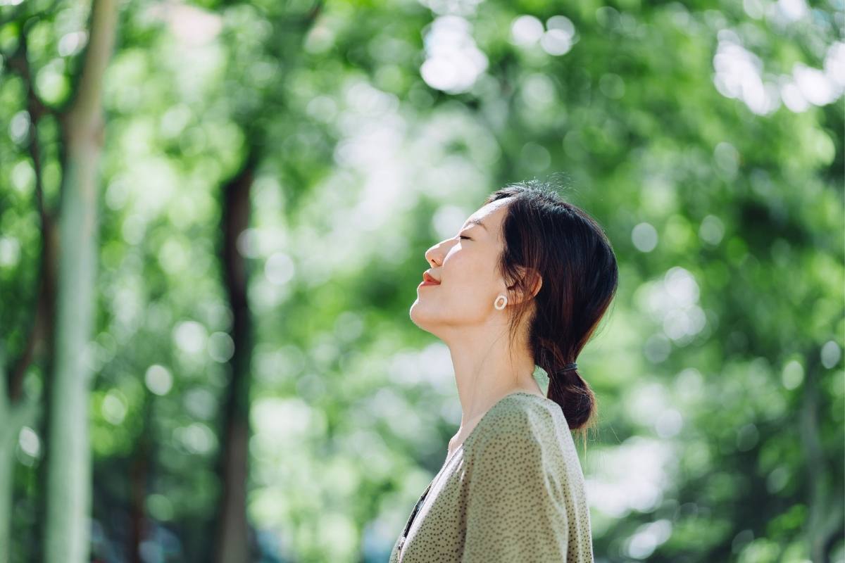 Relaxed woman breathing in surrounded by trees