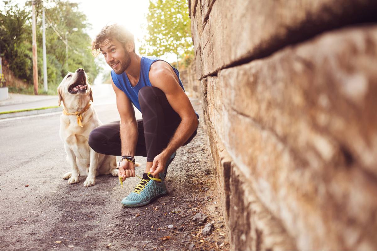 Young healthy man with his dog smiles, about to go for run 
