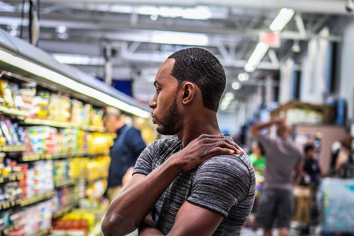 Man in grocery store rubbing shoulder