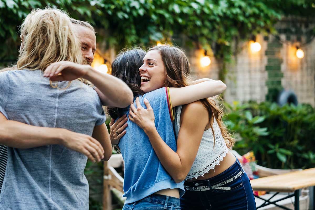 Group of young adult friends outdoors hugging