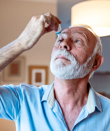 Man using eye drops while recovering from Cataract surgery