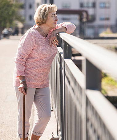 Woman recovering from knee replacement surgery looking over a bridge