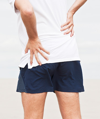Man holds back with hip joint pain