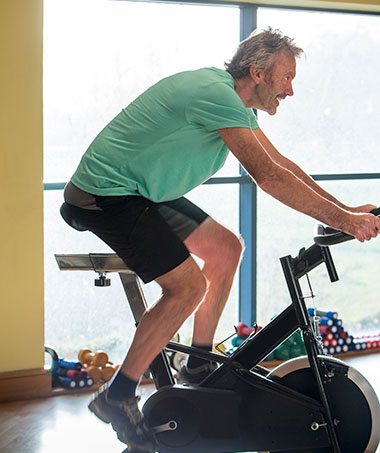 Man riding exercise bike as a hip replacement alternative