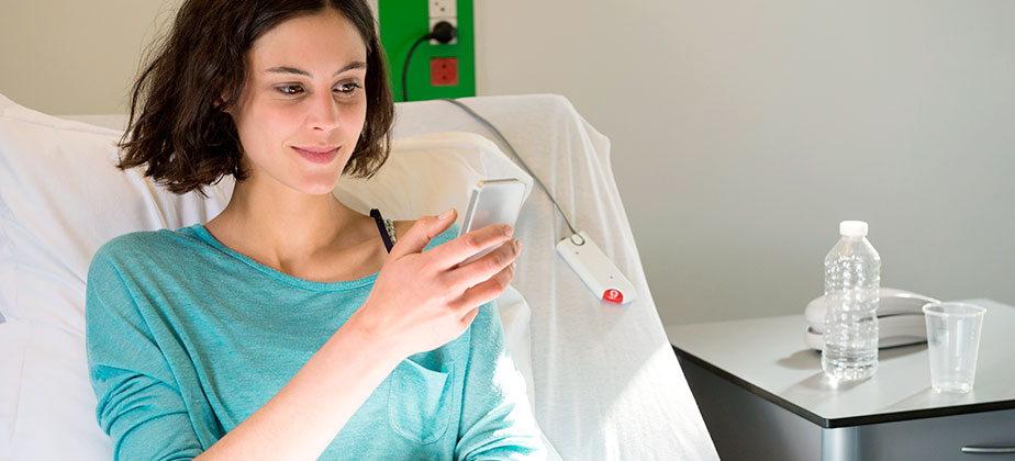 Woman sitting in a hospital bed looking at her phone
