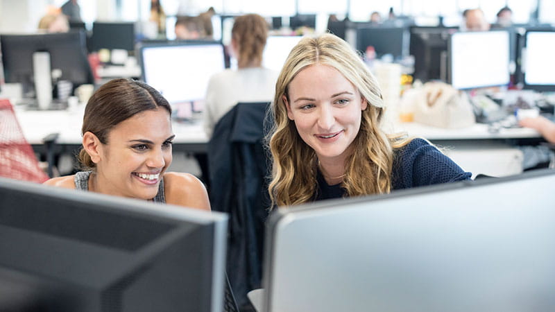 Two young women in office looking at computer screen
