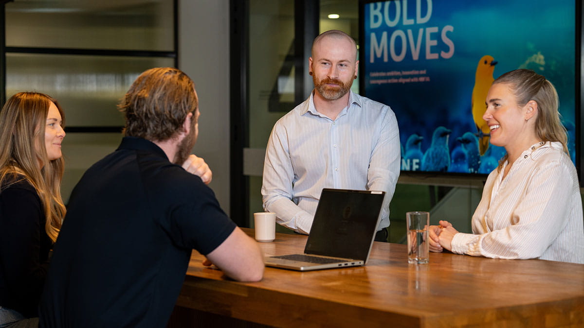 Four HBF employees meeting around a table in the Perth office, collaborating on ideas that support innovation, workplace culture and member outcomes.