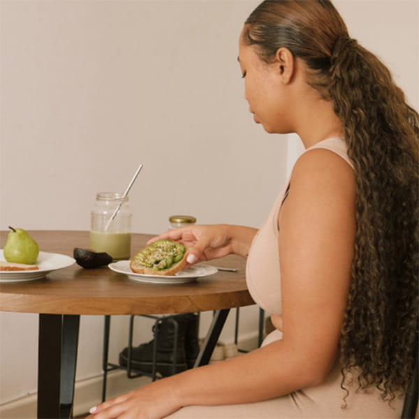 Woman sitting at table eating avocado on toast